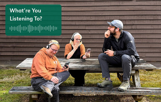 Three people listening to podcasts on a picnic table