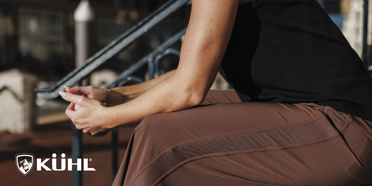 Man wearing KÜHL clothing standing on a dock beside a boat